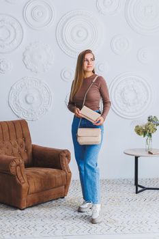 Stylish look. Close-up of beige handbag in hands. Fashionable girl. Close-up photo of a girl with a handbag in her hands.