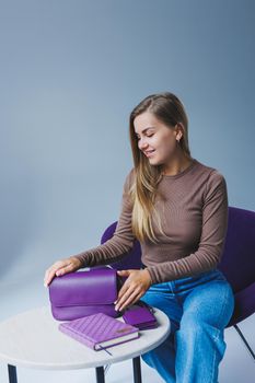 A purple leather bag in a girl's hand. Woman with luxury bag.