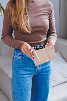 A beautiful woman holds a beige leather purse in her hands. Small women's handbag