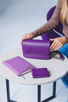 A purple leather bag in a girl's hand. Woman with luxury bag.