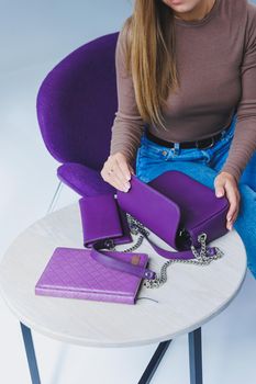 A purple leather bag in a girl's hand. Woman with luxury bag.