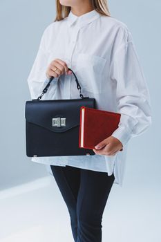 Black classic leather bag in a girl's hand. Woman with luxury bag.