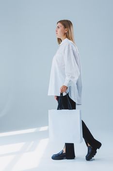 Stylish woman on a white background with a shopping bag. Eco bag for shopping.