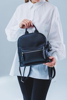 Black leather backpack in a woman's hand. A man with a luxurious leather backpack. Women's bags