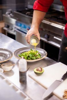 Chef seasoning delicious salade in his restaurant kitchen