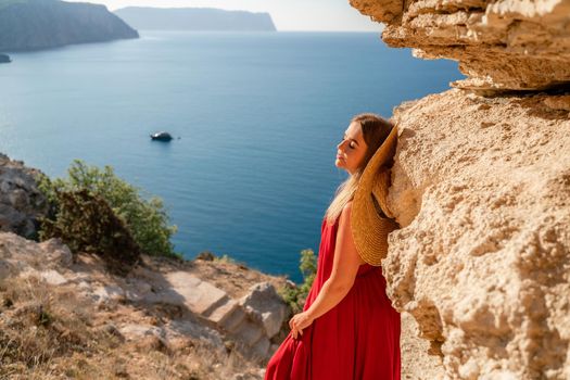 A woman in a red flying dress fluttering in the wind, against the backdrop of the sea