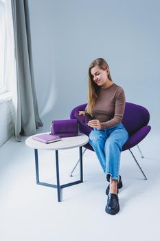 A purple leather bag in a girl's hand. Woman with luxury bag.