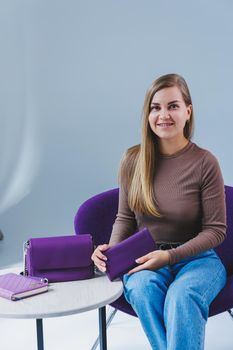 A purple leather bag in a girl's hand. Woman with luxury bag.