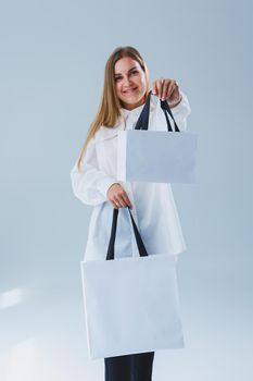 Stylish woman on a white background with a shopping bag. Eco bag for shopping.