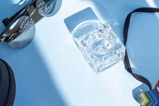 A glass glass of water on a blue background and and sunglasses.,,