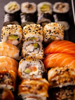 Delicious plate of variety of fresh sushi on dark stone