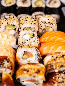 Lot mix variety of sushi rolls on black stone background in studio photo