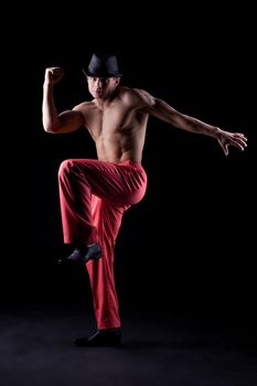 Full length portrait of muscular dancer in hat