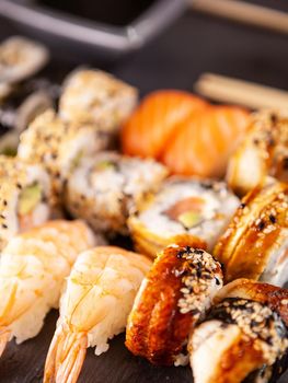 Close up view variety of sushi on black stone background