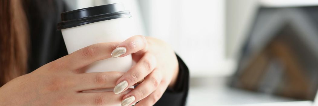 Close-up of woman with manicure hold cup of coffee, posing on working place in office. Break for lunch, enjoy drink, take pause. Chill, relaxation concept