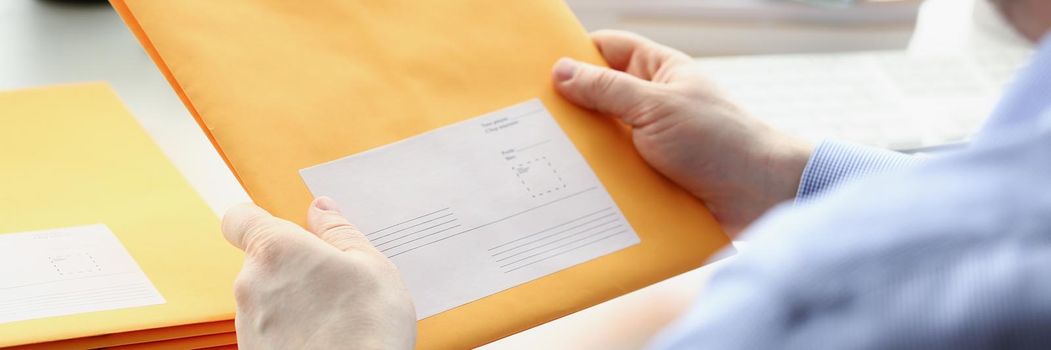 Close-up of man hold envelope, prepare package to give to courier for further delivery. Write address space on package. Delivery service, transfer concept