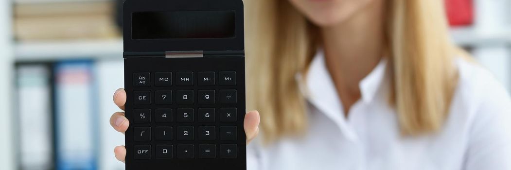 Portrait of smiling businesswoman accountant holding calculator in hand demonstrates display counting equipment. Finance, economy, banking, office concept