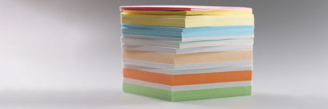 Close-up of uneven stack of sticky post it note on grey surface, bunch of clean papers. Bright pages for writing ideas, plans. Stationery, creative concept