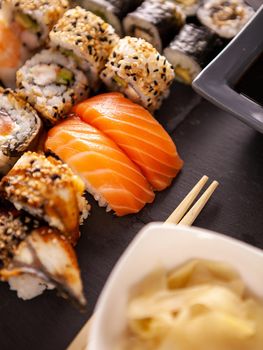 Close up view variety of sushi on black stone background