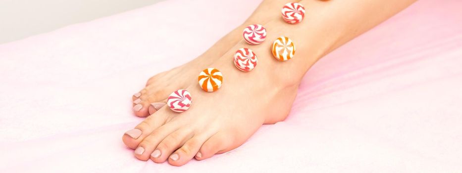 Depilation, waxing concept. Round candies lying down in a row on the female leg, close up