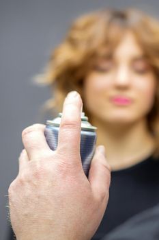 The hairdresser is using hair spray to fix the hairstyle of the young caucasian woman in the hairdresser salon, close up