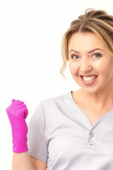 Happy caucasian woman doctor wearing pink gloves celebrates and raising fists on white background