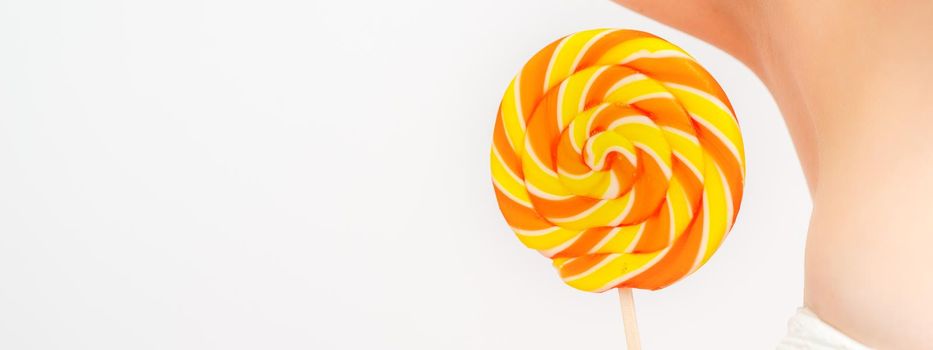 Waxing, depilation concept. A young female holds a round lollipop near her armpit on white background