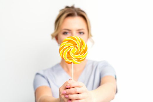 Waxing, depilation concept. The beautician is wearing a medical coat holding a sugar lollipop on white background