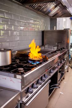 Chef making flambe fois gras in restaurant kitchen