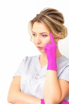 Young caucasian female doctor wearing gloves thoughtful looking away isolated on white background