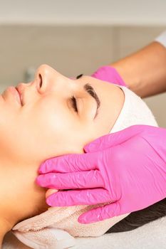 Cosmetologist with gloved hands applies a moisturizing mask with peeling cream on the female face. Facial cosmetology treatment. Procedures for facial care