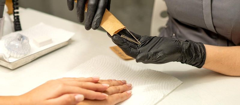 Manicure master takes out manicure tools from a kraft envelope in a nail salon