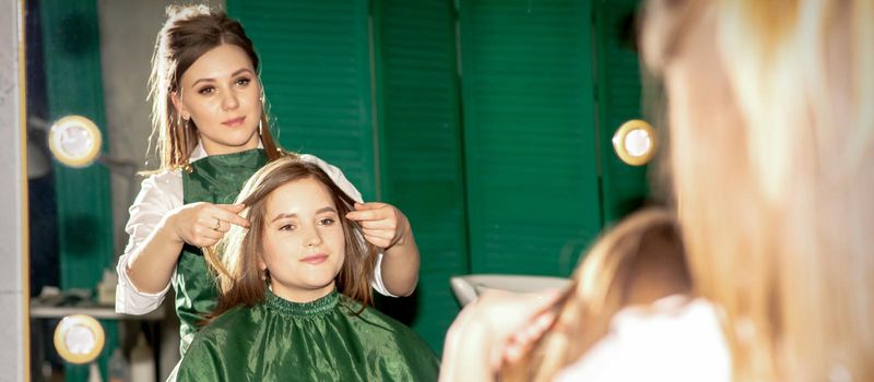 Professional hair care. Beautiful young caucasian brunette woman with long hair receiving hairstyling in a beauty salon