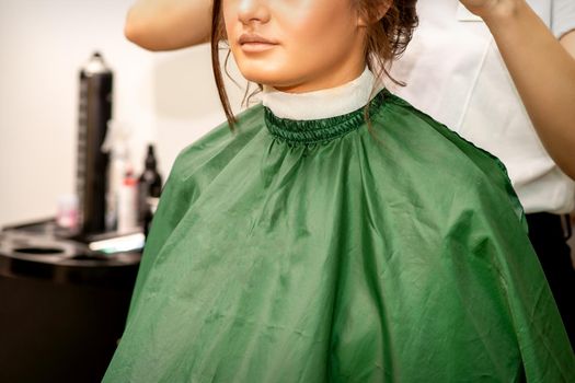 Hairstyling bride. A female hairdresser makes styling hair for the beautiful young caucasian woman in a beauty salon