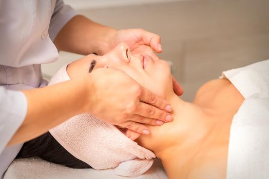 Facial massage. Young caucasian woman getting a massage on her neck in a beauty clinic