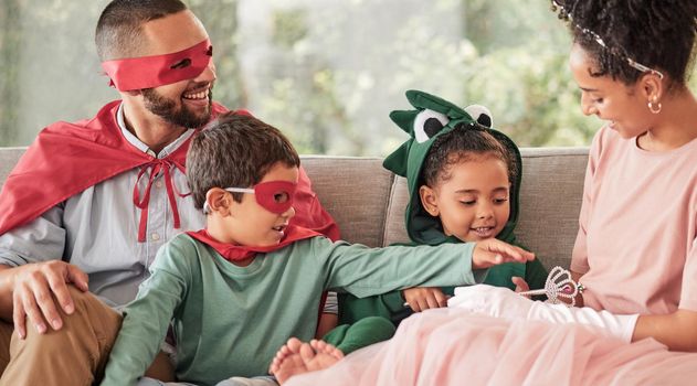 Family, children and halloween with kids and parents in costume while sitting on a sofa in the living room of their home. Love, imagination and celebration with a brother and sister dressing up.