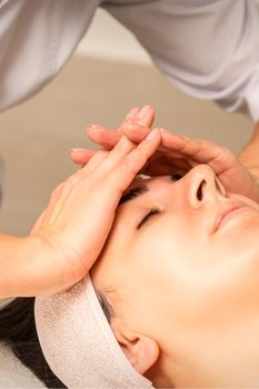 Facial massage. Young caucasian woman with closed eyes getting a massage on her forehead in a beauty salon