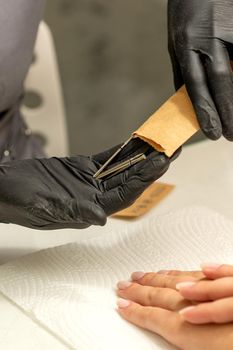 Manicure master takes out manicure tools from a kraft envelope in a nail salon