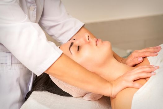 Young caucasian woman with closed eyes getting a chest massage in a beauty clinic