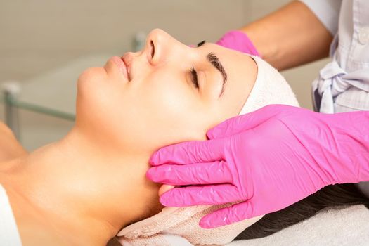 Cosmetologist with gloved hands applies a moisturizing mask with peeling cream on the female face. Facial cosmetology treatment. Procedures for facial care