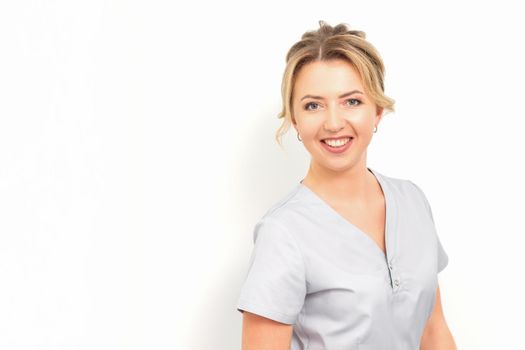 Close-up portrait of young smiling female caucasian healthcare worker standing staring at the camera on white background