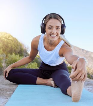 Workout yoga stretch, music streaming headphones and woman outdoor on a mat. Portrait of a happy smile from female wellness, exercise and healthy stretching before training in nature on a mountain.