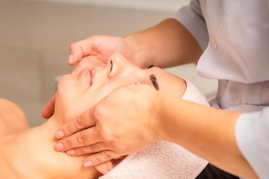 Facial massage. Young caucasian woman getting a massage on her neck in a beauty clinic