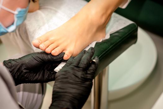 The podiatry doctor examines the toenails on the female foot