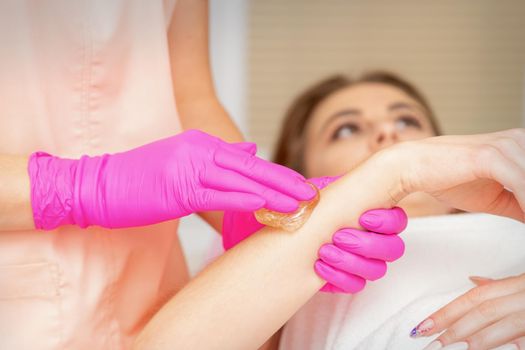 Waxing. Depilation hand and arm of the young woman lying in the spa salon