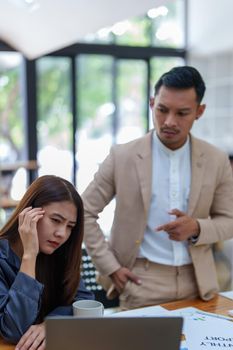 portrait of a female marketing worker showing a worried expression after being reprimanded by a male business owner for failing to meet the company's sales targets.