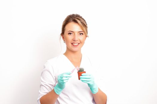 A smiling female beautician holds little green cactus with the razor in her hands. Hair removal concept
