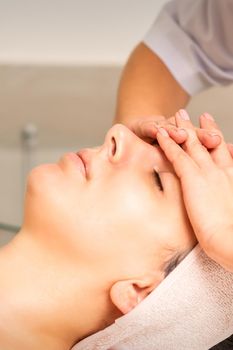 Facial massage. Young caucasian woman with closed eyes getting a massage on her forehead in a beauty salon