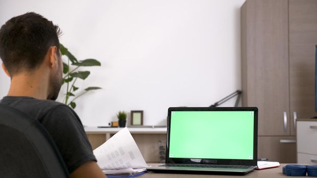 Business man with beard working hard at his desk in the living room of his house