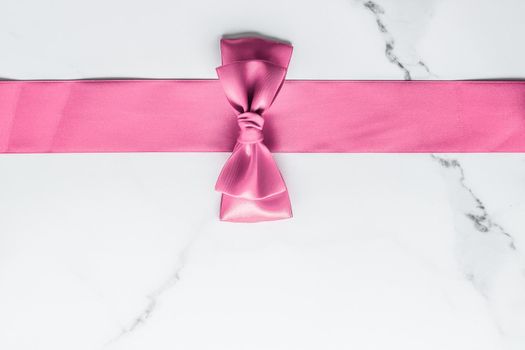 Birthday, wedding and girly branding concept - Pink silk ribbon and bow on marble background, girl baby shower present and glamour fashion gift decor for luxury beauty brand, holiday flatlay design